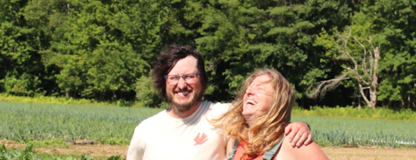 Two smiling farmers standing together in a vegetable field