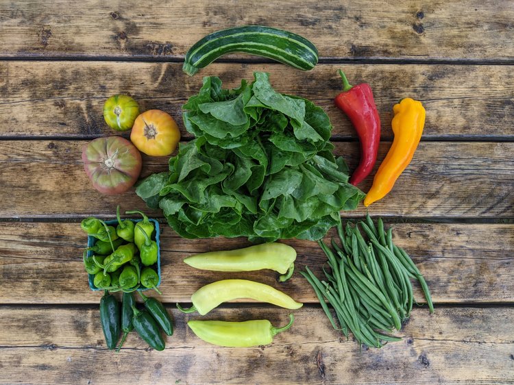 Fresh vegetables arranged in a basket on a wooden table